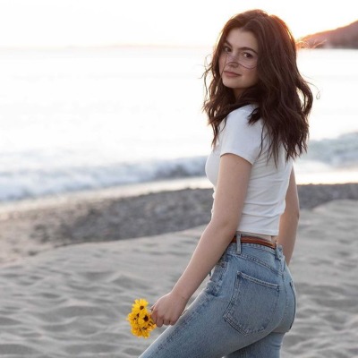 Finn William Leeves Coben's sister, Isabella Kathryn Coben posing on a beach while holding sunflowers.